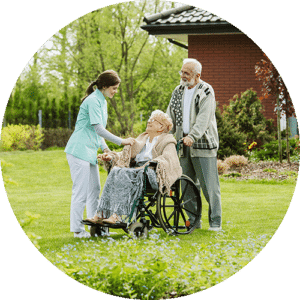 Elderly woman in wheelchair with her husband and carer in the backyard