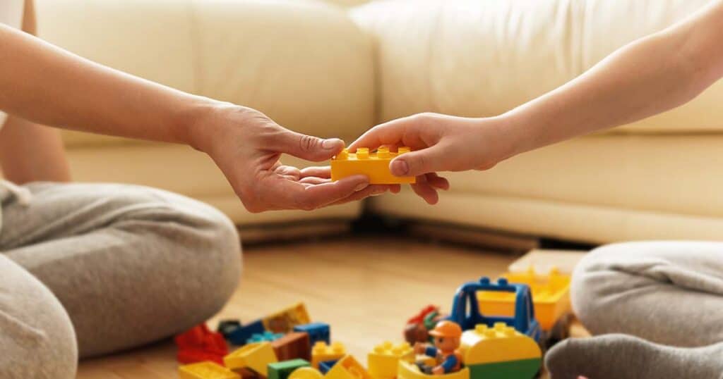 Parent handing child toy.